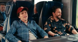 Jesse Eisenberg and Kieran Culkin share a smile as they ride on a train in "A Real Pain."