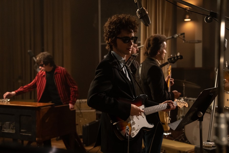 Timothée Chalamet playing guitar in a recording studio.