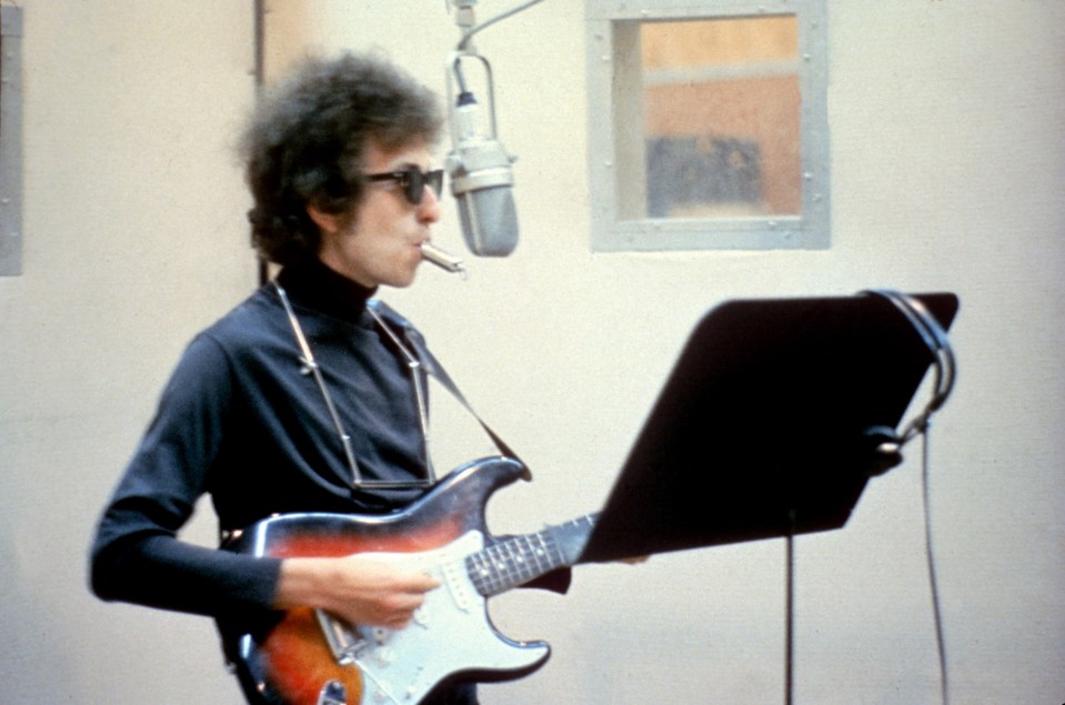 Bob Dylan playing guitar in a recording studio.