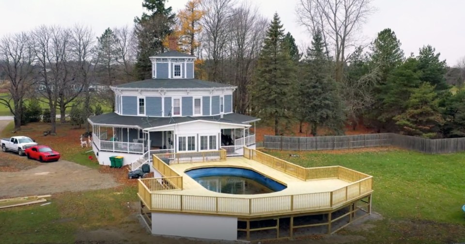 Aerial view of a blue octagonal house with a new pool and deck.