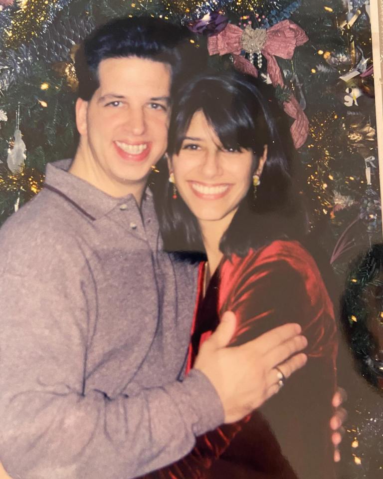 Couple posing together in front of a Christmas tree.