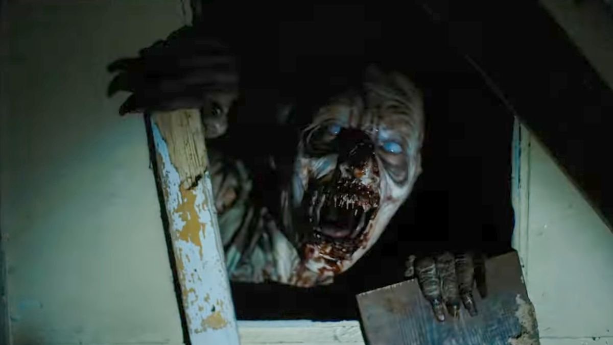 a zombie like creature reaches from a hole in a door in until dawn trailer