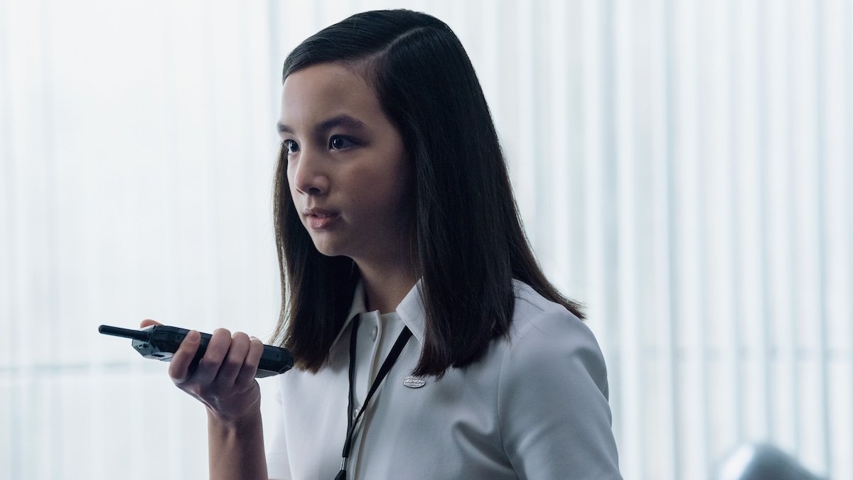 A young girl in a white shirt holds a walkie to her mouth on Severance