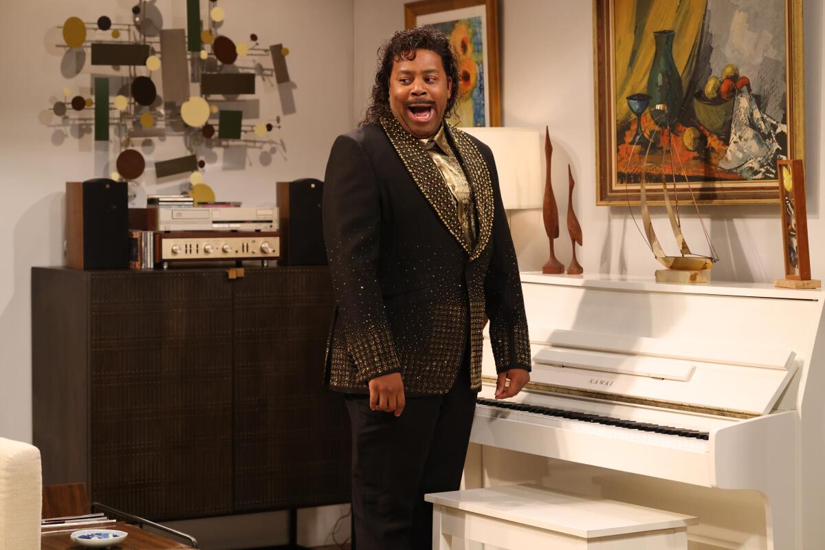 A man dressed as Little Richard in a black suit adorned with sequins.