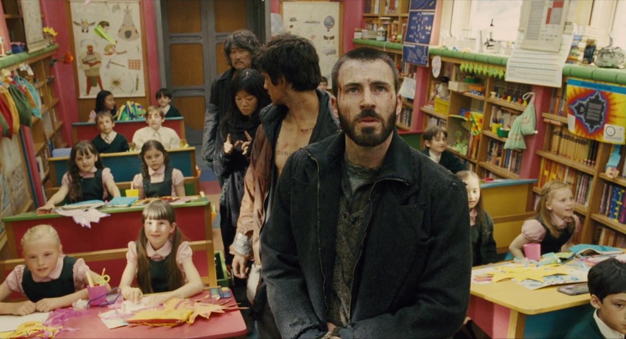 Chris Evans and a group of people dressed in ragged clothing standing in a brightly lit classroom in Snowpiercer.