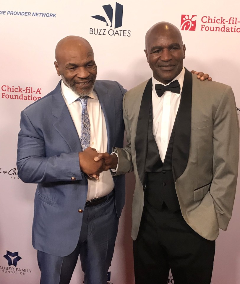 two men shaking hands in front of a chick-fil-a foundation sign