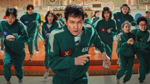 image of player 456 and other track suit wearing people in squid game season two trailer for Netflix price increase article