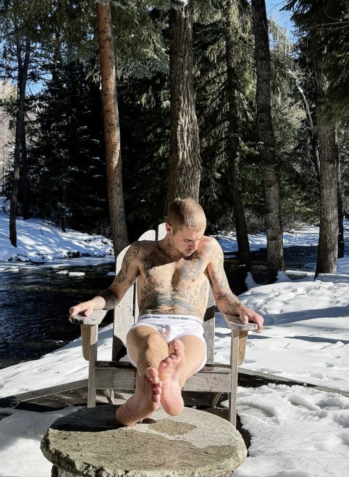 Justin Bieber in Calvin Klein underwear sitting in a wooden chair in the snow.