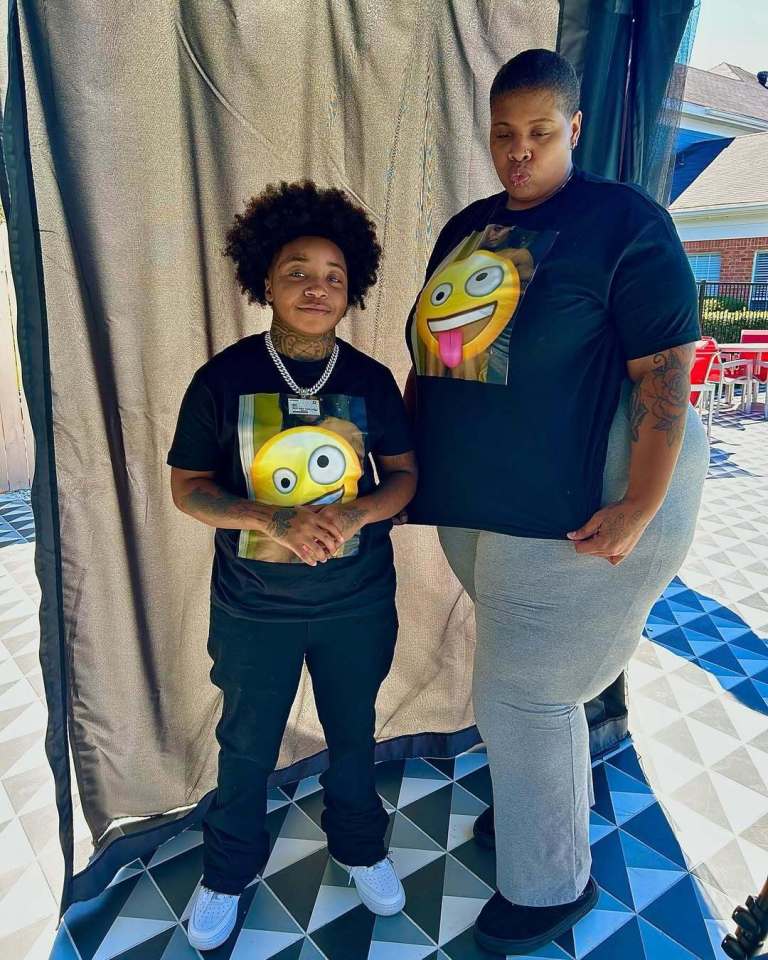 Two people wearing matching emoji t-shirts.