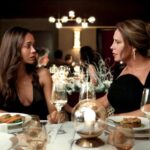 Two women talk at a table at a banquet hall