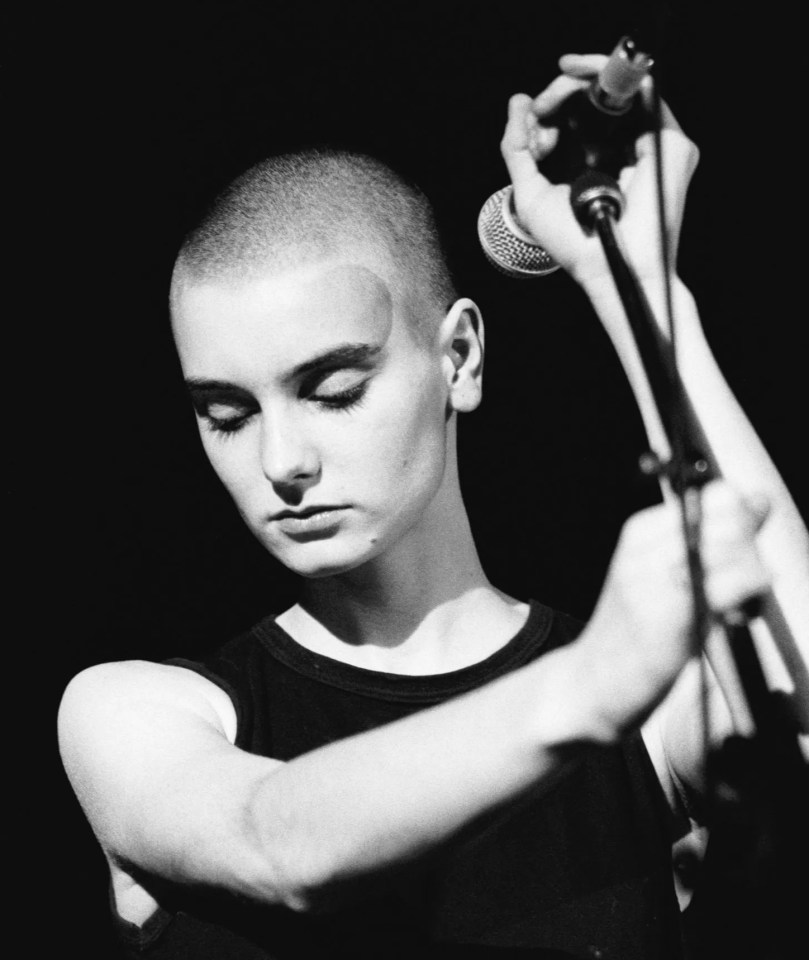 Black and white photo of Sinead O'Connor performing.