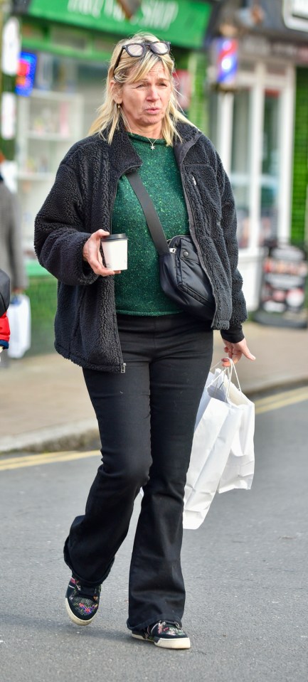 Zoe Ball walking down the street, carrying shopping bags and a coffee.