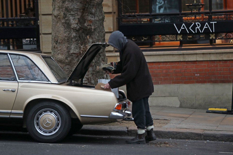 Man loading shopping bags into the trunk of a vintage Mercedes.