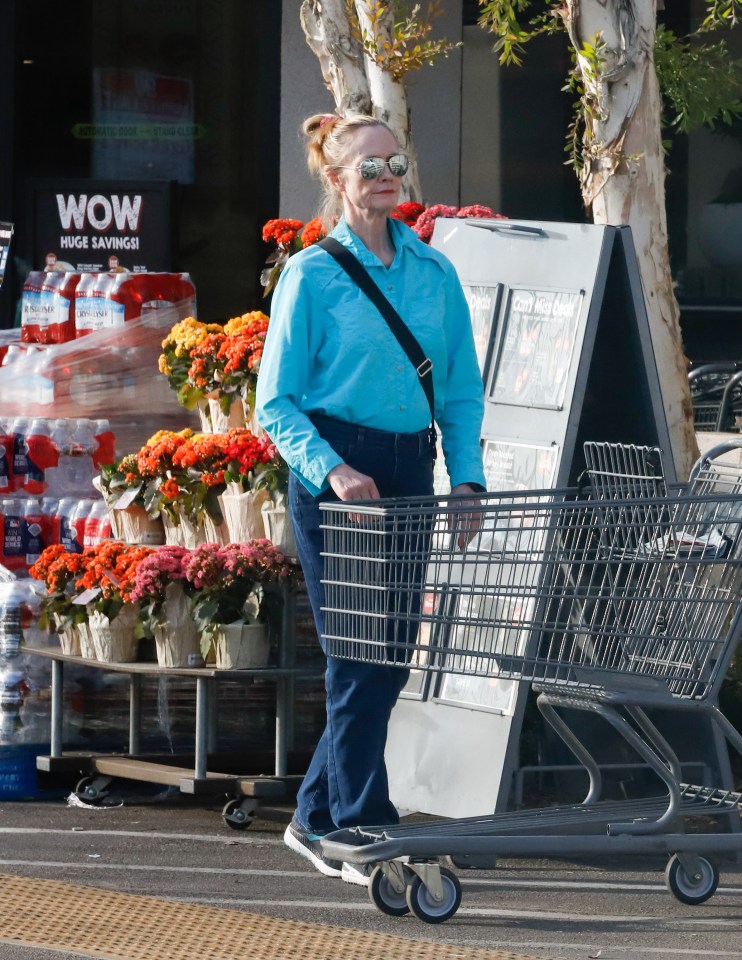 Cybill Shepherd pushing a shopping cart outside a grocery store.