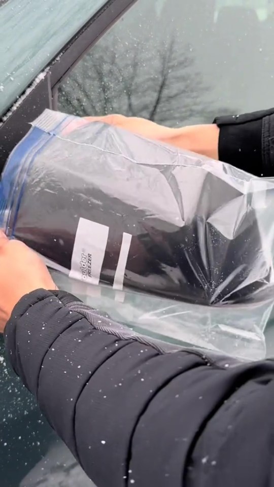 Person placing a freezer bag against a car window.