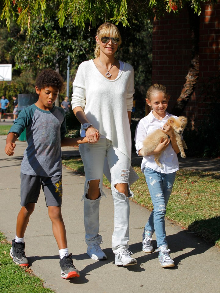 Heidi Klum walking with her children and a small dog.