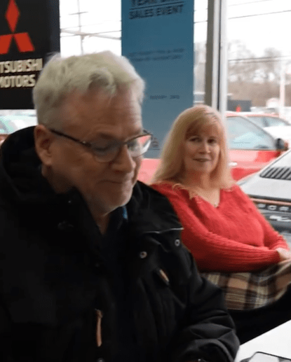 A man and woman sitting in a car dealership.