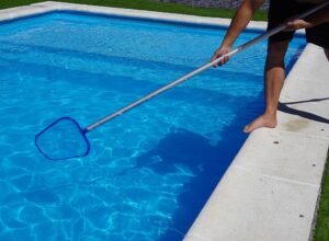 A man cleaning a swimming pool with a net