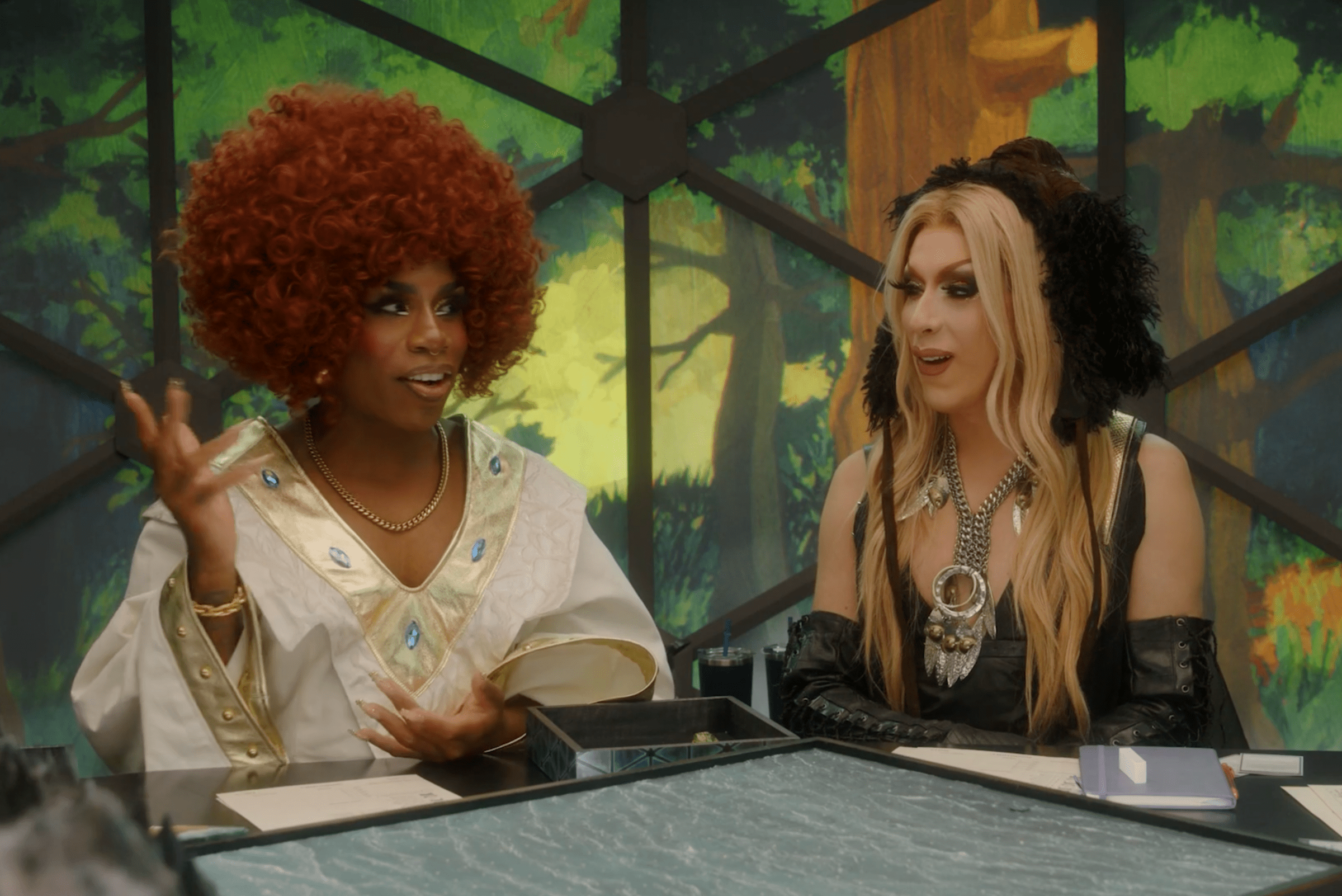 Monet X Change and Alaska Thunderfuck sitting in the Dimensional Dome in Dungeons and Drag Queens.