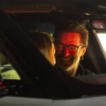 Hugh Jackman and Sutton Foster in a car.