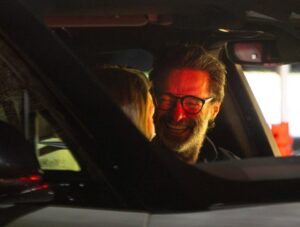 Hugh Jackman and Sutton Foster in a car.