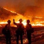 Firefighters observing a wildfire at night.