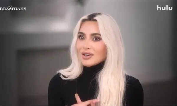 Kim Kardashian in a black turtleneck, speaking in a promotional image for The Kardashians season 6.