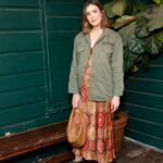 Woman in green jacket and patterned dress.