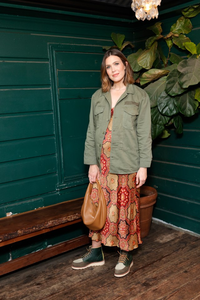 Woman in green jacket and patterned dress.