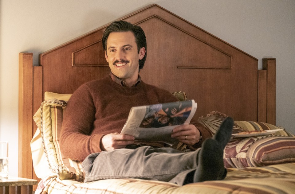 Milo Ventimiglia as Jack in This Is Us, reading a newspaper in bed.