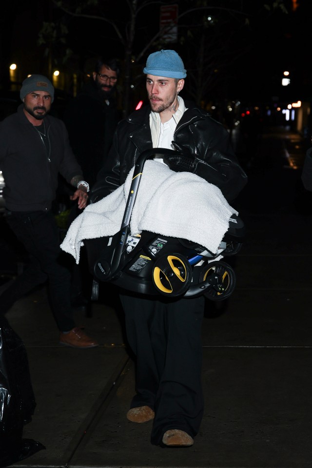 Justin Bieber carrying a baby in a car seat.