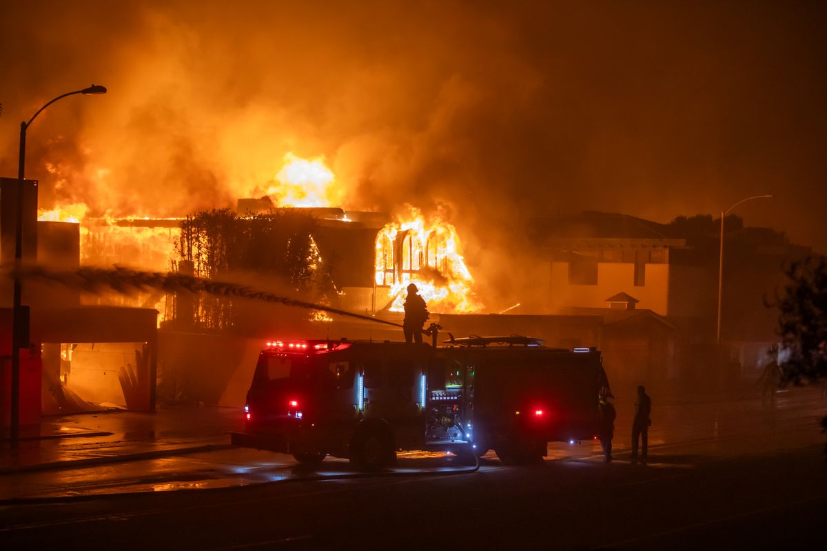 Firefighters battle the Palisades Fire while it burns homes on the Pacific Coast Highway amid a powerful windstorm on January 8, 2025 in Los Angeles, California.  The fast-moving wildfire has grown to more than 2900-acres and is threatening homes in the coastal neighborhood amid intense Santa Ana Winds and dry conditions in Southern California. 