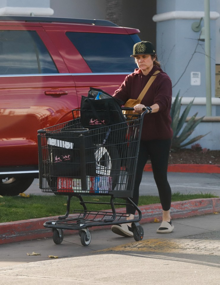 Tiffani Thiessen pushing a shopping cart in a parking lot.