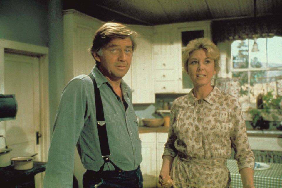 Still image from *The Waltons* showing Ralph Waite and Michael Learned in a kitchen.