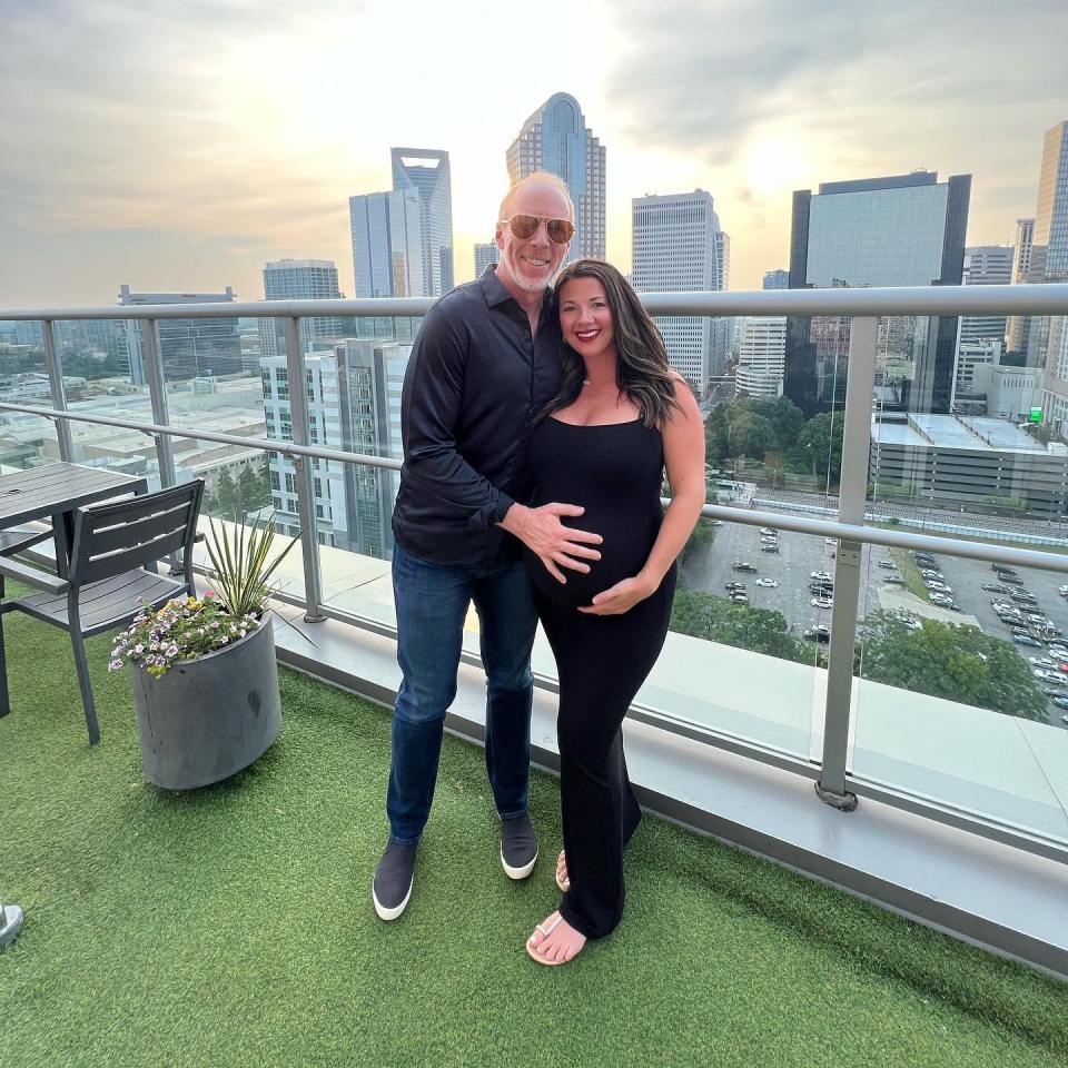 Pregnant woman and her fiance on a rooftop overlooking a city.