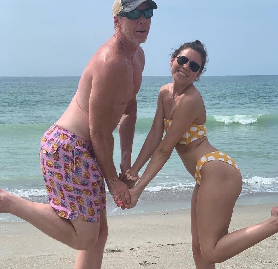 A man and woman holding hands on a beach.