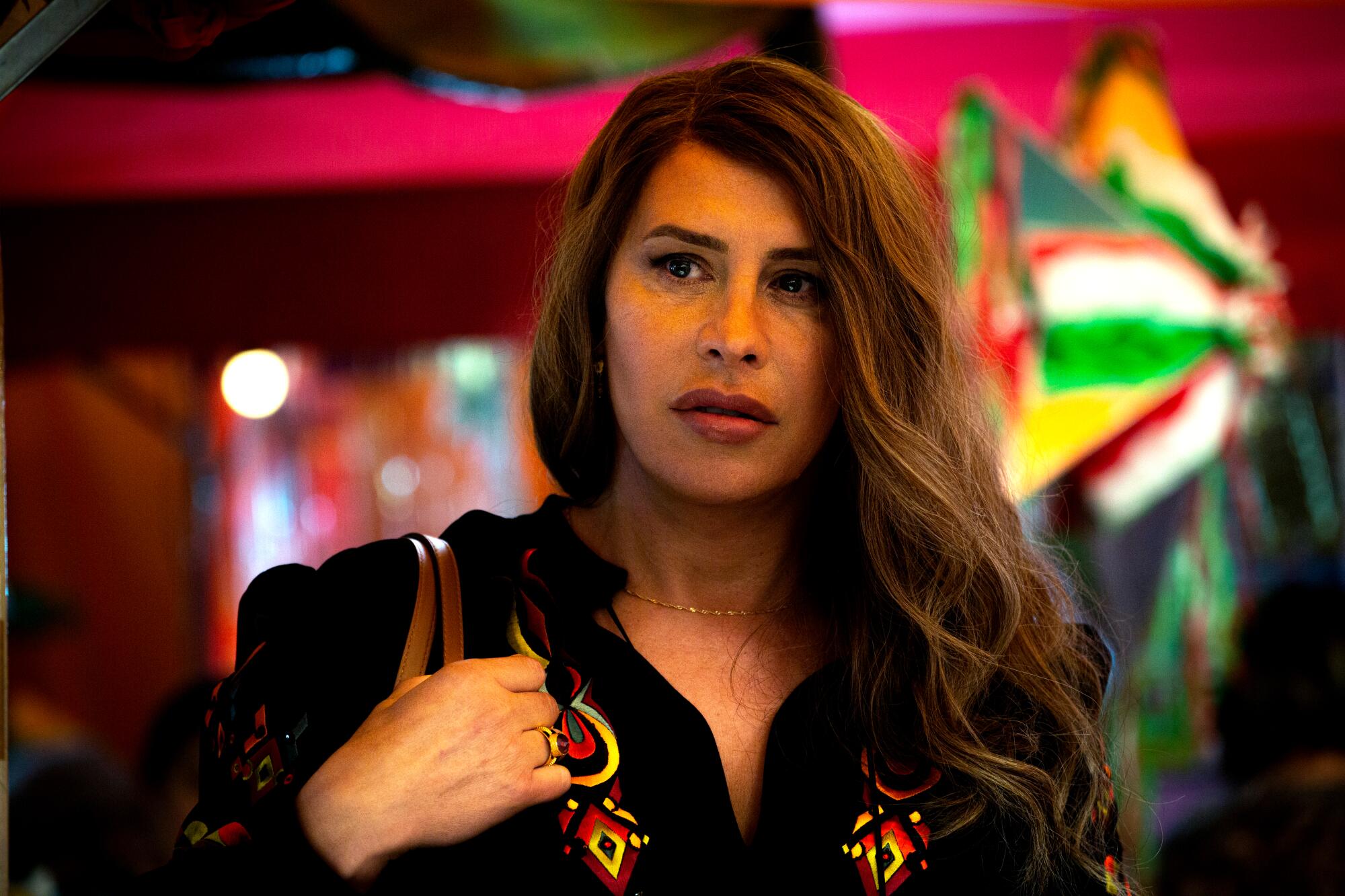 A woman looks serious as she walks througha colorful market in “Emilia Pérez.”