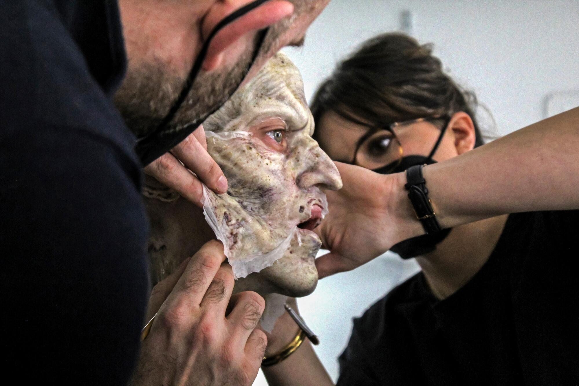 Special effects artists apply makeup to actor Bill Skarsgard.