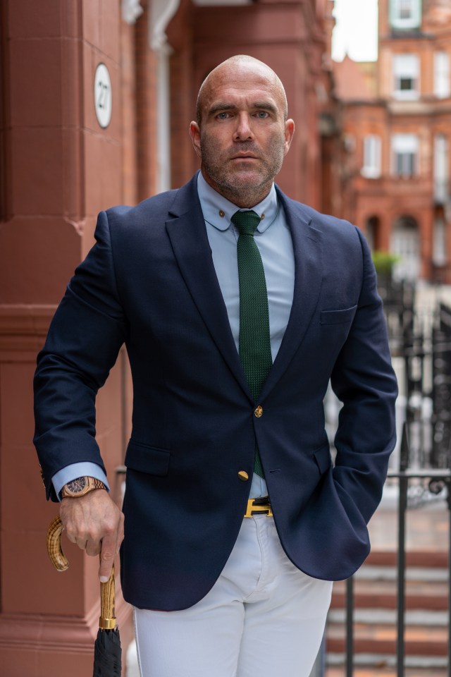 Portrait of a man in a suit holding an umbrella.