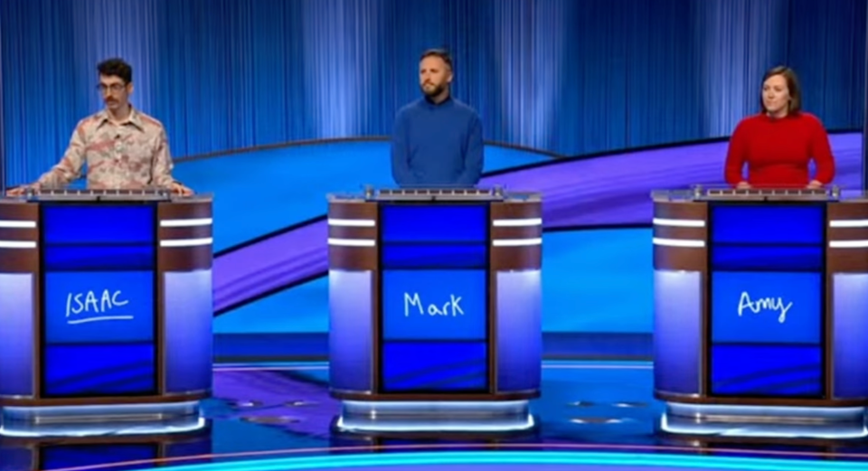 Isaac Hirsch, Mark Fitzpatrick, and Amy Hummel at podiums on a game show set.