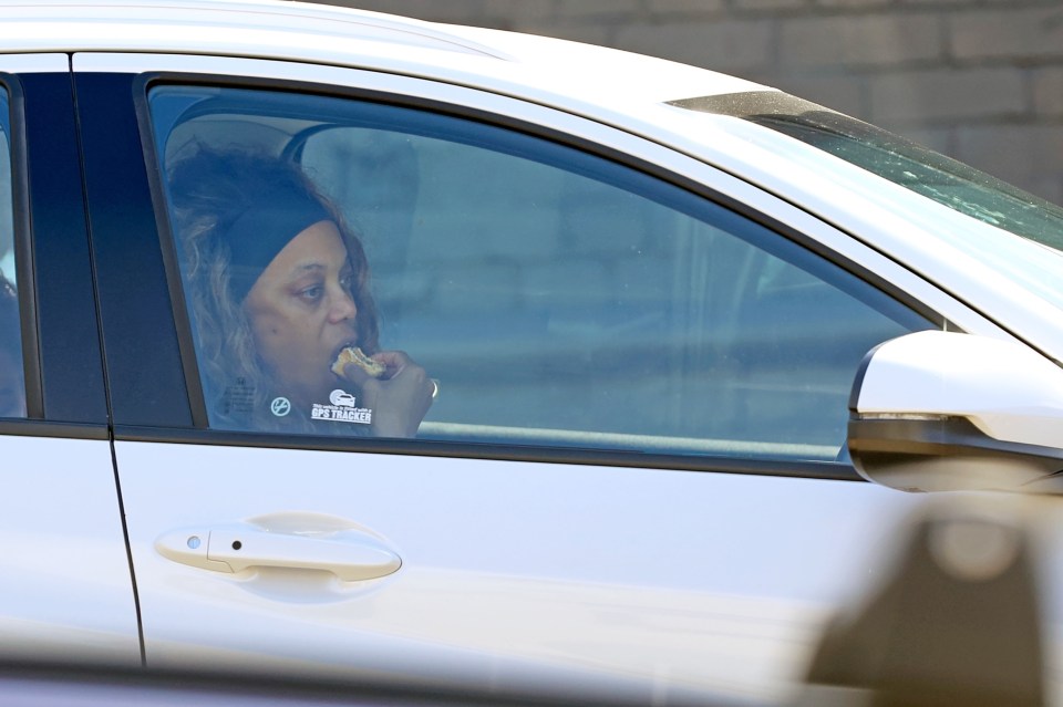 Tyra Banks eating a cheeseburger in a car.