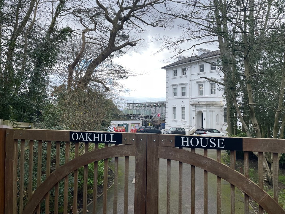 Oakhill House gate with a large white house undergoing renovations visible beyond.