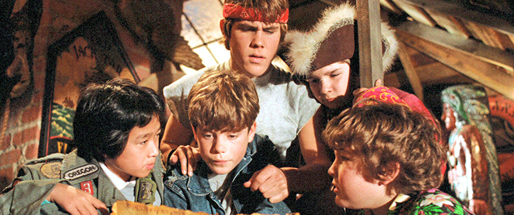 The Goonies cast looking at a treasure map.