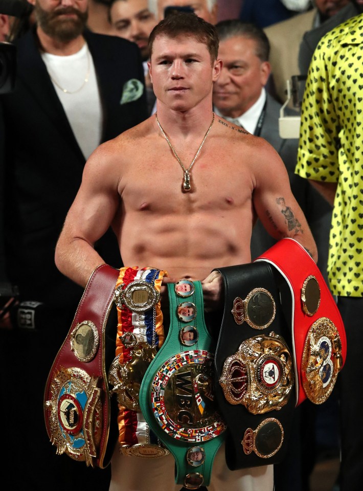 Canelo Alvarez holding his boxing championship belts.