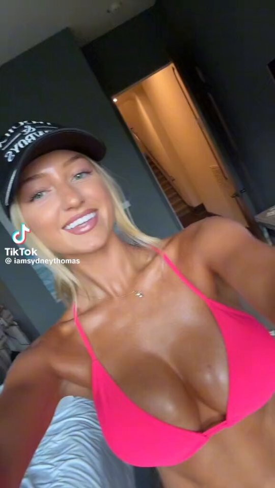 Woman in pink bikini top and baseball cap.