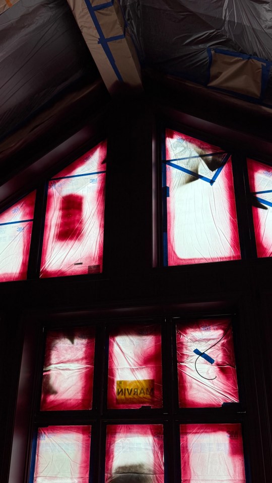 Windows covered in red paint protection film during a home renovation.