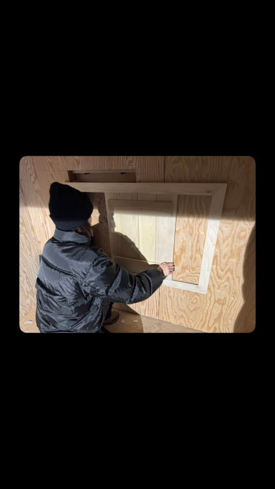 Person installing light-colored wood paneling in a new home.