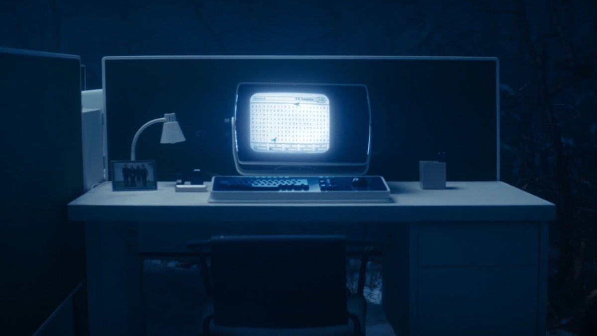 A computer and desk with flies on it at night in the woods on Severance