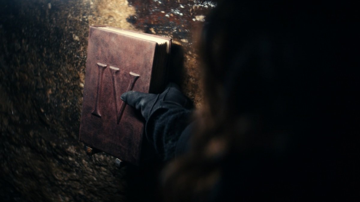 A woman with a gloved hands holds a red book with a big Roman IV on Severance