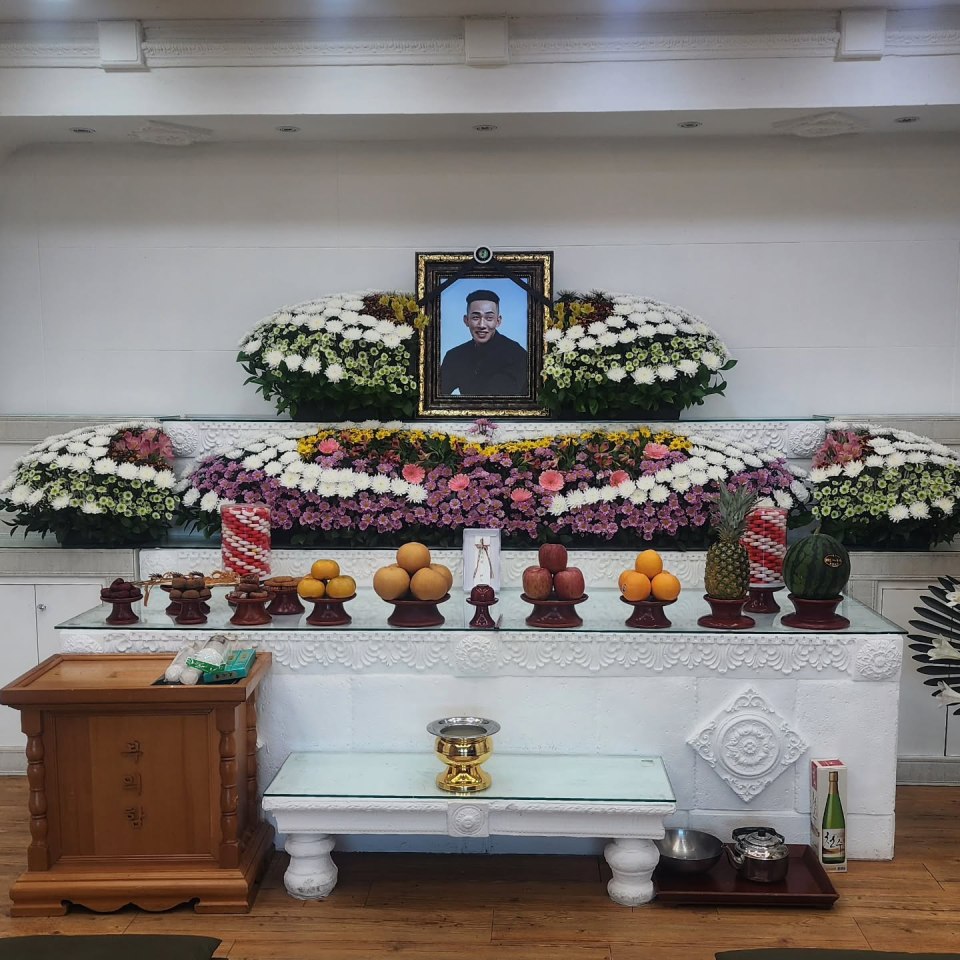 Funeral service with portrait and floral arrangements.